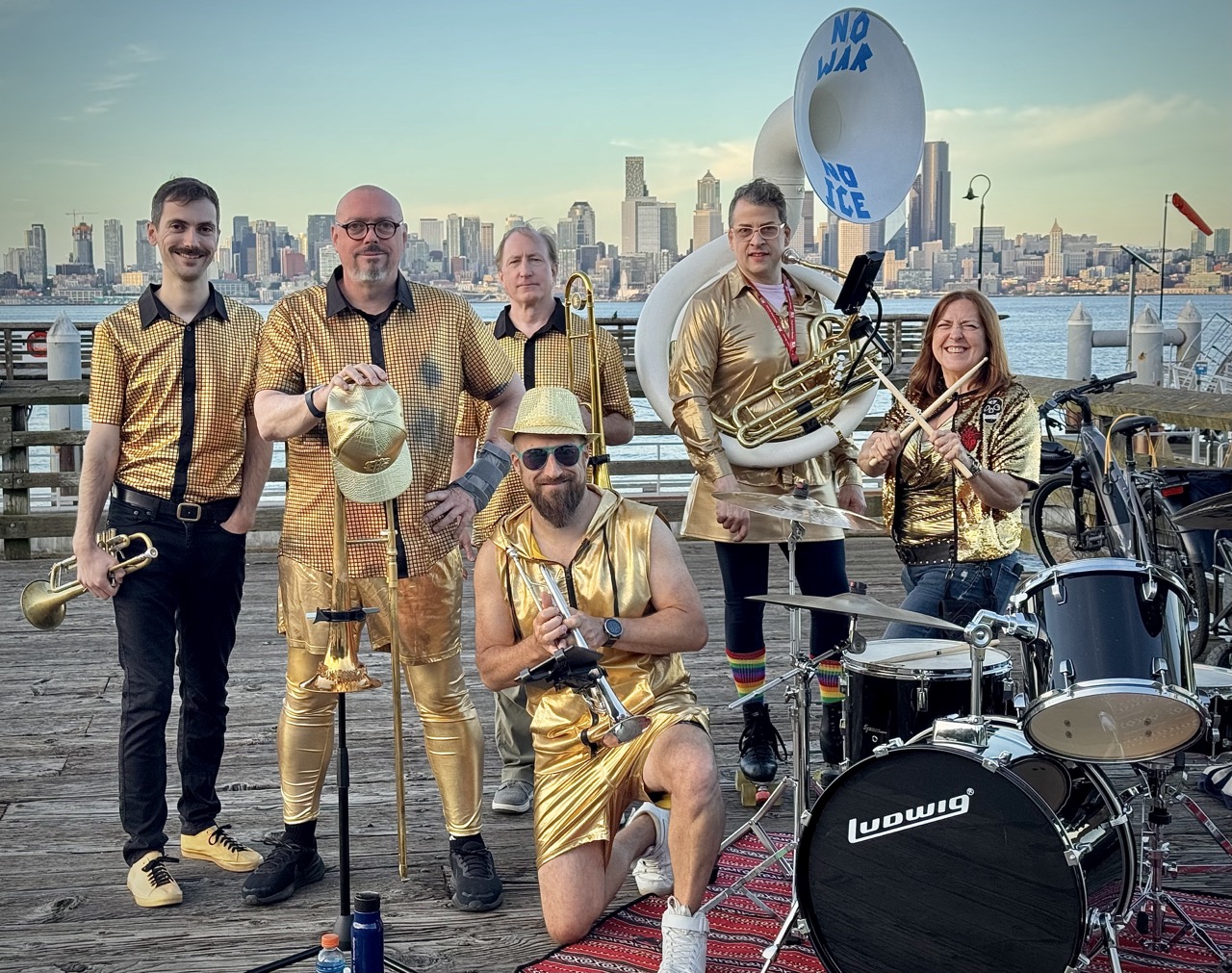 People posing for the camera with brass instruments and percussion dressed in metallic gold clothes.